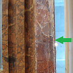 Een vrijgelegd stukje originele marmering op de pilaster