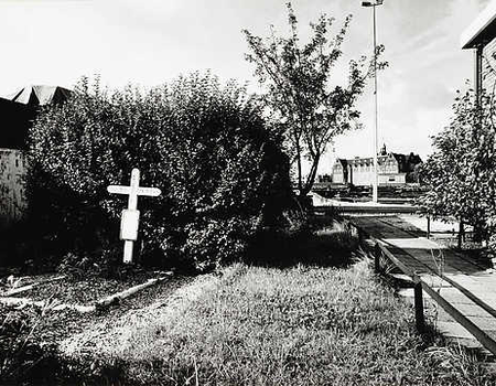 Het kruisje van de liefdevolle buurtbewoners op de plek waar Keesje is doodgeschoten. Op de achtergrond het Lloydhotel.