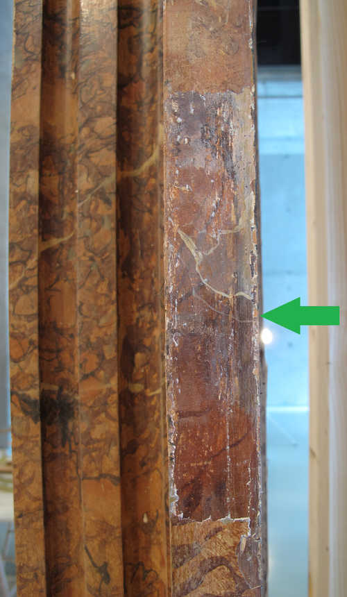 Een vrijgelegd stukje originele marmering op de pilaster