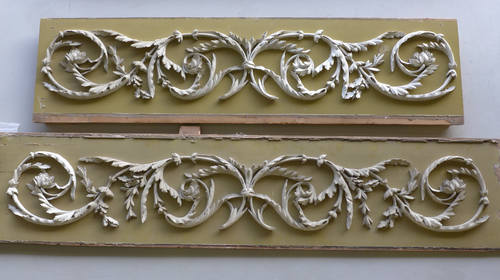 Boven het  originele houtsnijwerk paneel van de schouw, onder het latere pâte-ornamentpaneel.