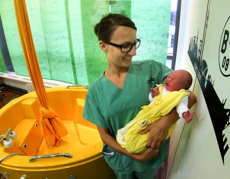 Vroedvrouw Kirsten Orlowski heeft baby Renesmee in haar armen.  Zij is ter wereld gekomen in de Borussia Dortmund (Duitsland) verloskamer. Of zij ook zelf fan zal worden is nog even de vraag… Foto Dieter Menne