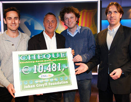 Johan Cruijff krijgt een cheque aangeboden. Op de foto v.l.n.r.: Rens den Hollander Johan Cruijff, Michiel Verhaar , Maarten Nooter (hoofdredacteur NOS Sport)