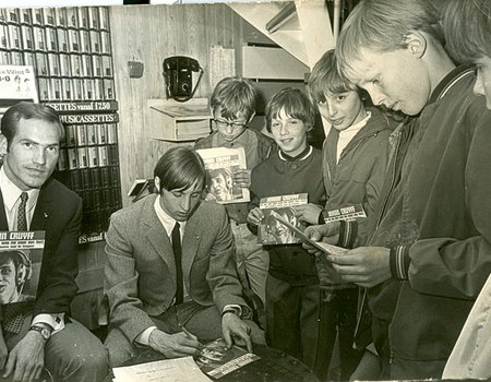 Johan zet handtekeningen op zijn eerste grammafoonplaatje, onder het toeziend oog van René Leijen (met bril)