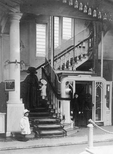 Interieurfoto van modehuis Maison de Bonneterie, kort na de opening van het nieuwe pand aan de Kalverstraat-Rokin, 1909. Rechts is de lift te zien, gemaakt van geslepen spiegelglas en voorzien van fluwelen bankjes.