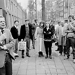 Eerste paal voor de nieuwe publieksingang aan de Nieuwezijds mei 1986. (Carry midden met de armen over elkaar)